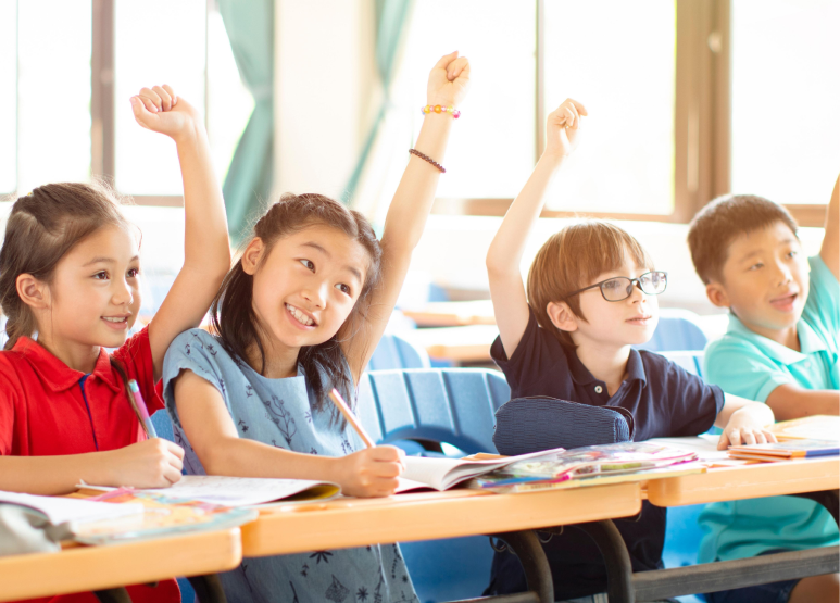 Children raising hands in class